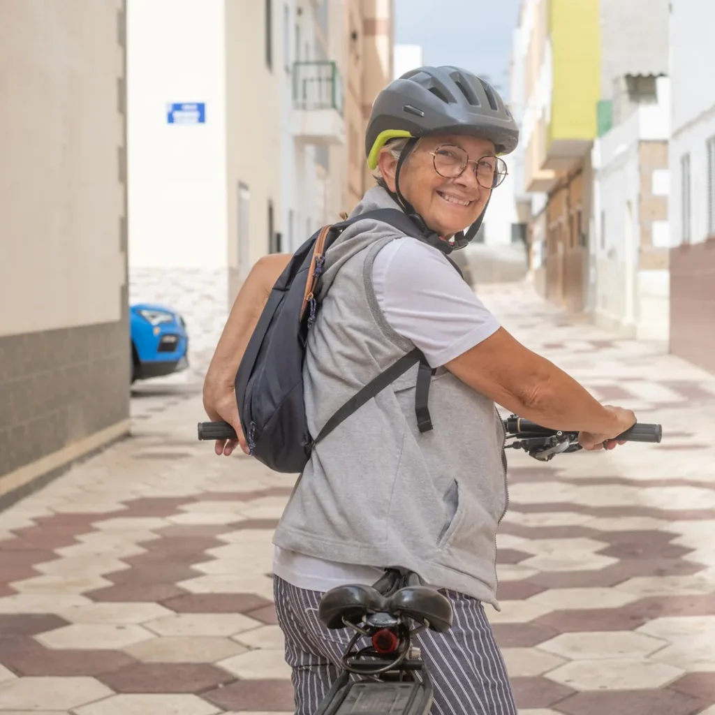 Cuánto cuesta un seguro de bicicleta en Zaragoza: mujer mayor sonriente con gafas, casco y mochila