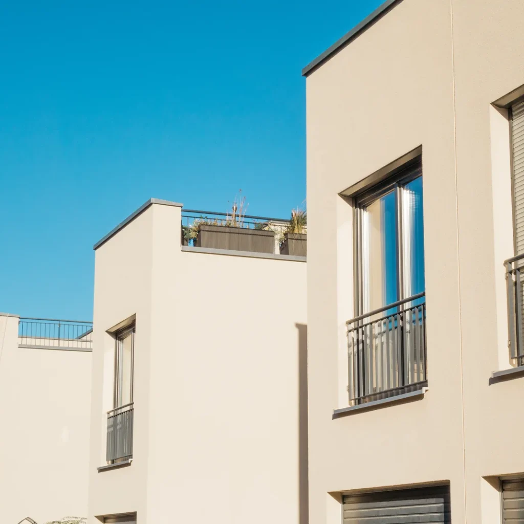 Cuánto cuesta un seguro de casa en Madrid: hilera de casas adosadas de fachada clara con balcones y azoteas con plantas