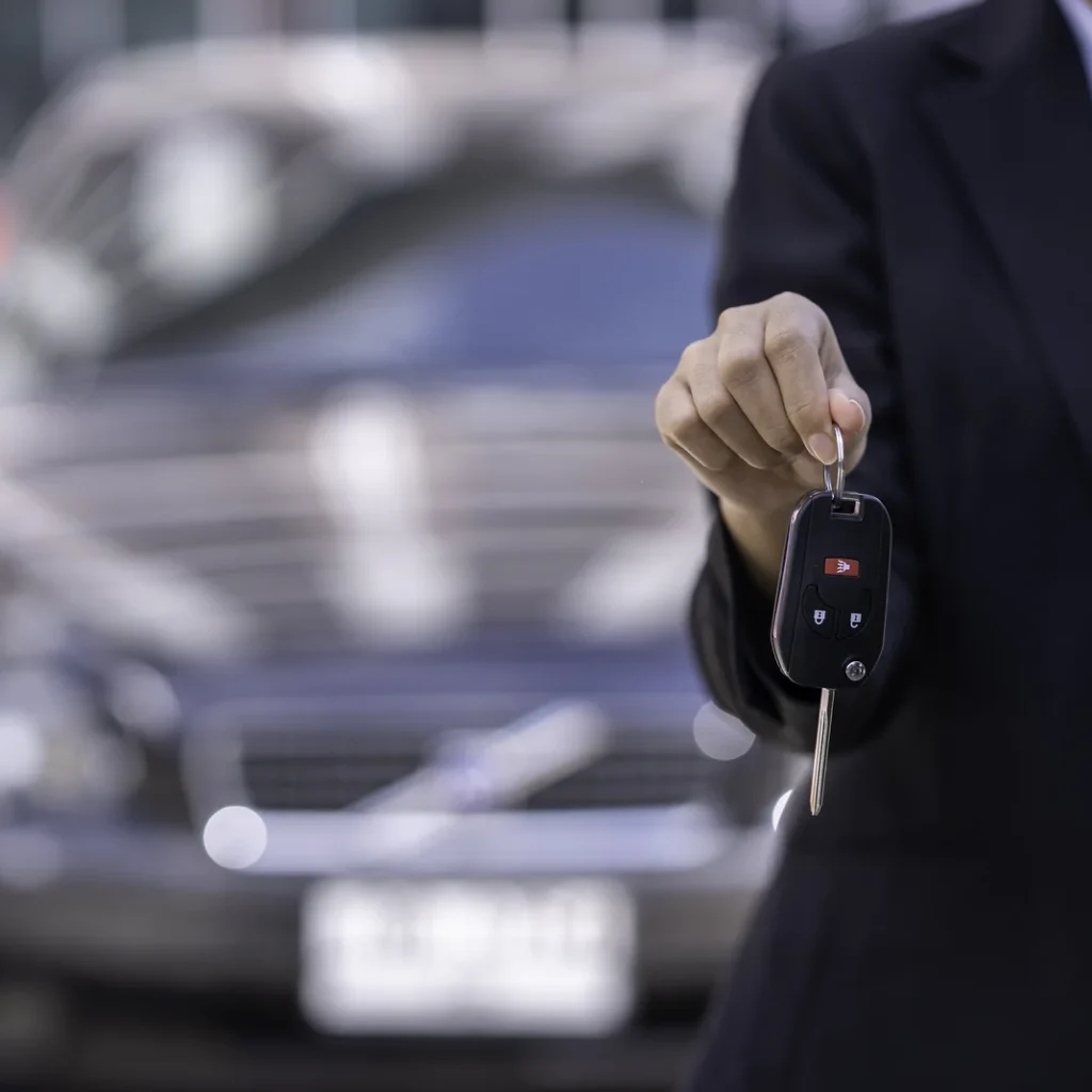 Cuánto cuesta un seguro de coche en Madrid: mano que entrega la llave de un coche delante de un turismo