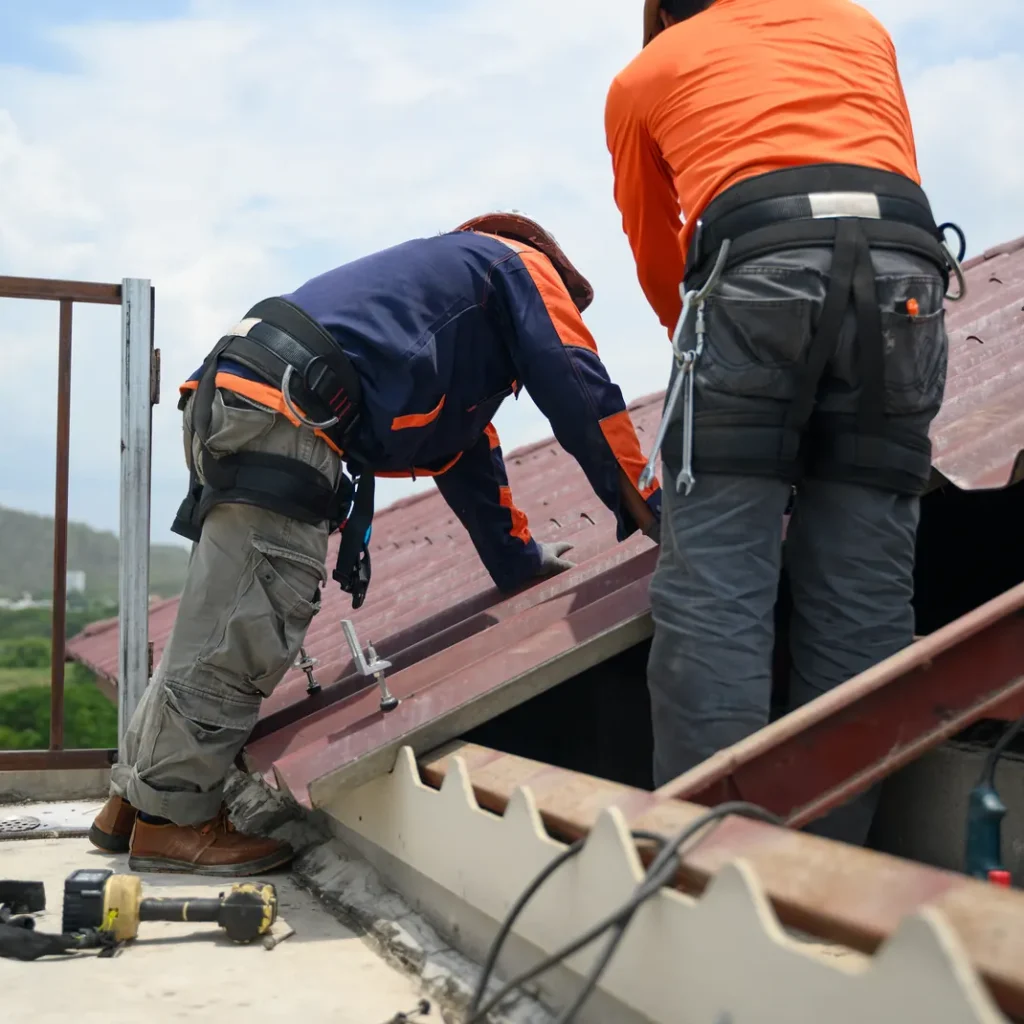 Cuánto cuesta el seguro de convenio de construcción en Madrid: dos operarios con casco y arnés anticaída en un tejado