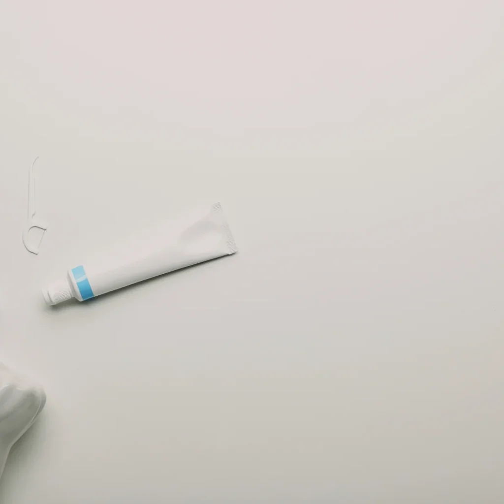 Cuánto cuesta un seguro dental en Madrid: cepillo, hilo dental y pasta junto a un modelo de muela sobre una mesa