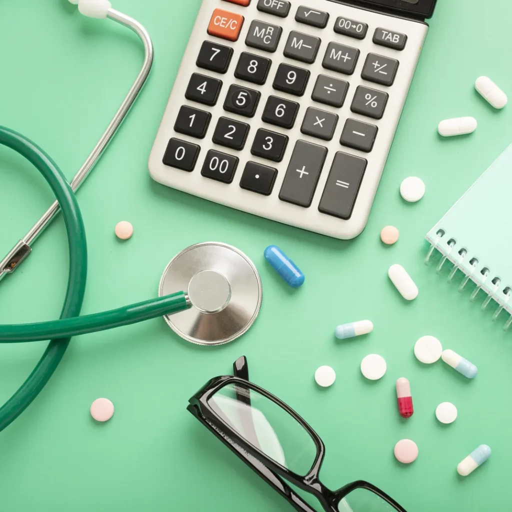 Cuánto cuesta un seguro médico privado en Zaragoza: fonendoscopio, calculadora, pastillas y gafas sobre una mesa verde