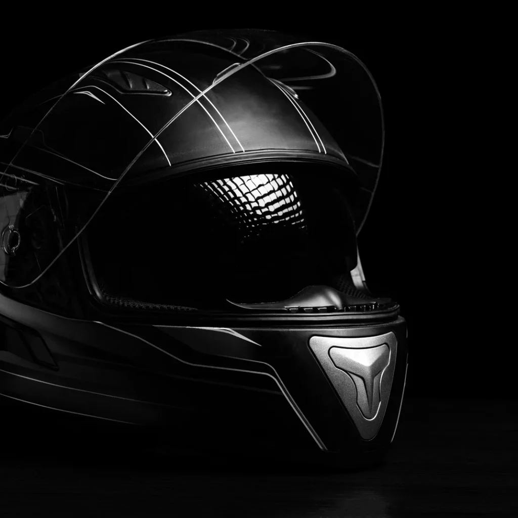 Cuánto cuesta el seguro de moto en Madrid: casco integral negro de moto con la visera levantada sobre fondo oscuro