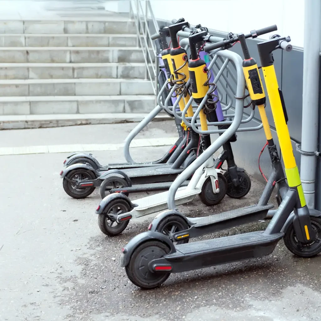 Cuánto cuesta un seguro de patinete eléctrico en Zaragoza: fila de patinetes eléctricos amarillos, uno blanco y otro morado