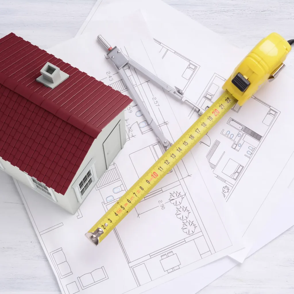 Cuánto cuesta un seguro de vida en Madrid: planos de una vivienda con una maqueta de casa sobre una mesa