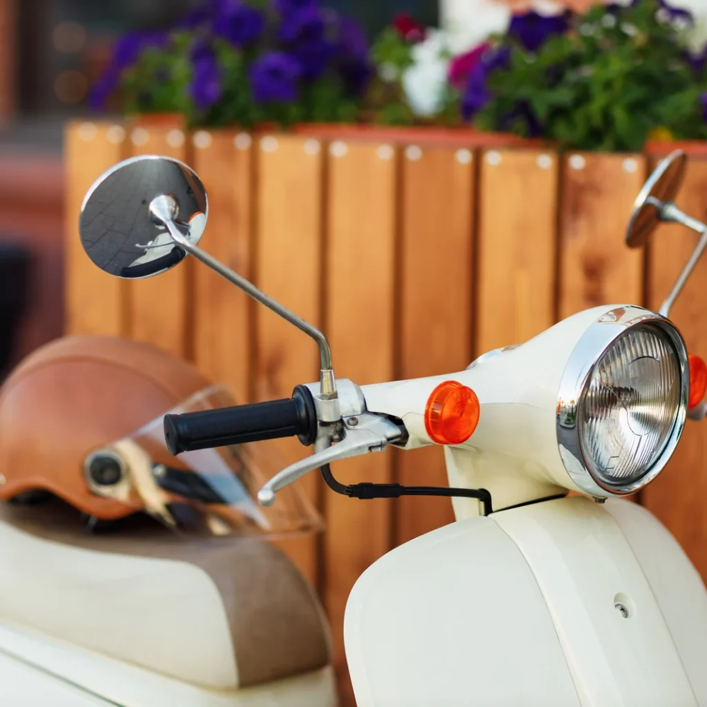 Precio del seguro de ciclomotor en Zaragoza: scooter clásico de color crema aparcado junto a una jardinera con flores