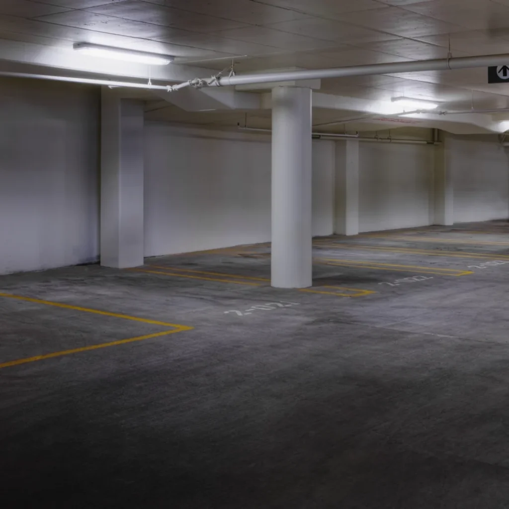 Seguro de coche barato en Madrid: plaza de garaje subterráneo con líneas amarillas y un coche aparcado