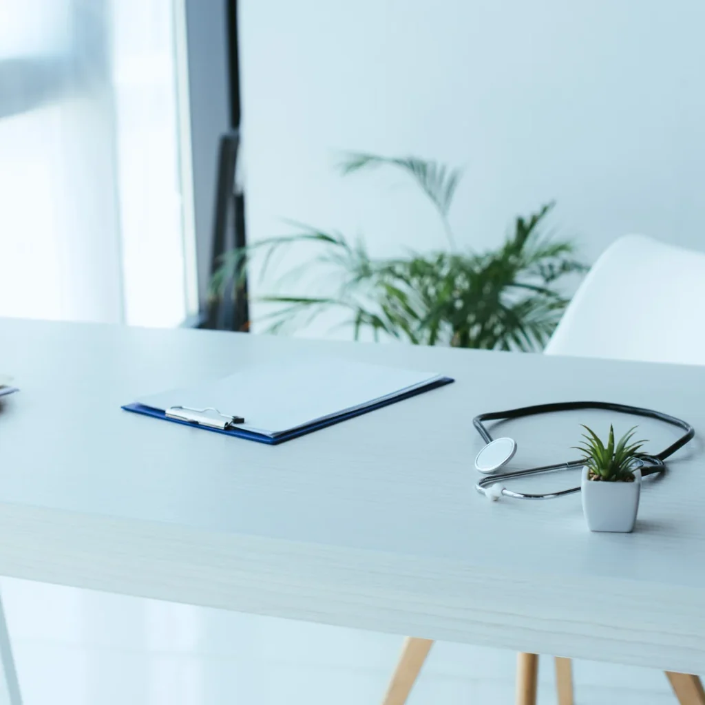 Seguros de salud baratos en Madrid: fonendoscopio sobre una mesa blanca de consulta con carpetas y un sujetapapeles